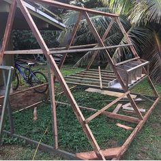 a wooden structure sitting on top of a lush green field next to a bike parked in front of it