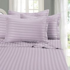 a bed with purple striped sheets and pillows