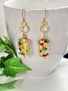 "Bold and beautiful Murano glass with splashes of gold, red, green and blue! These earrings remind me of an artists palette!  Made exclusively by artisans in Murano, Italy...they are THE masters of glass working!  The rectangle glass hangs on Vermeil gold charms of oval circles for fun and whimsy! The earrings hang 2.25- inches on gold Vermeil ear wires. So versatile and easy to wear with any outfit. You will love these earrings. A wonderful gift for any occasion and arrives in a standard gift b Handmade Multicolor Glass Earrings, Elegant Gold Murano Glass Earrings, Modern Gold Glass Earrings, Artistic Gold Jewelry For Festive Occasions, Unique Gold Glass Earrings, Nickel-free Multicolor Glass Earrings, Elegant Colorful Earrings As A Gift, Elegant Colorful Earrings For Gift, Colorful Glass Jewelry For Gifts