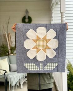 a person holding up a quilt with a flower on it