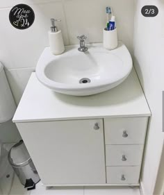 a white bathroom sink sitting on top of a counter next to a toilet paper dispenser