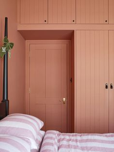 a bedroom with pink walls and striped bedspread