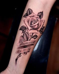 a black and white rose tattoo on the left arm with an old ribbon around it