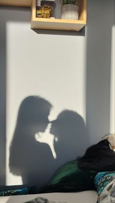 the shadow of a man and woman in front of a wall with books on it