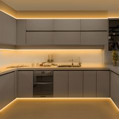 a kitchen with an oven, sink and dishwasher is lit up at night