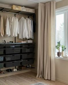 an open closet with clothes hanging on the rack and shoes in bins next to it