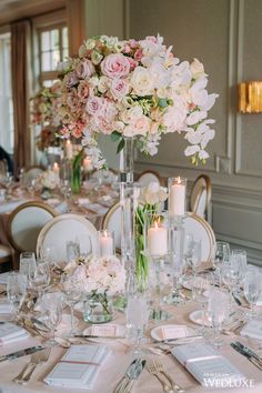 the centerpieces on this table are filled with pink and white flowers, candles, and silverware