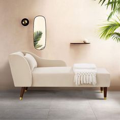 a white couch sitting in front of a mirror next to a potted palm tree