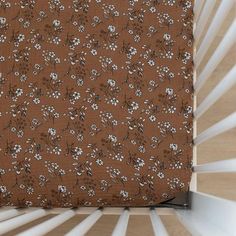 a brown and white flowered fabric with vertical blinds in the backround behind it