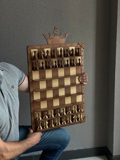 a man holding up a giant chess board