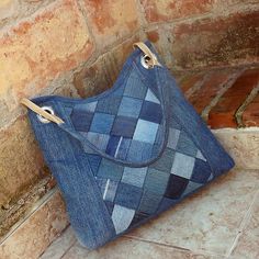 a blue purse sitting on the ground next to a brick wall