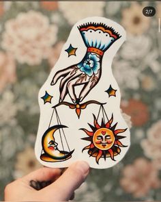 a person holding up a sticker with sun and moon designs on it's side