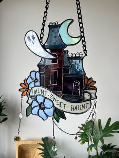 a stained glass clock hanging from the side of a wall with a house and moon on it