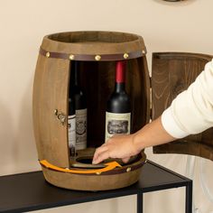 a person opening up a wine bottle in a barrel shaped container on top of a table