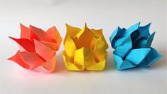 three different colored origami flowers sitting next to each other