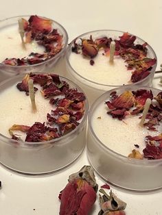 four cups filled with different types of food on top of a white table next to dried flowers