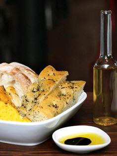 a white bowl filled with food next to a bottle of olive oil