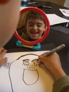 a young boy is smiling as he draws his own face in front of the mirror