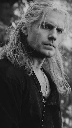 a black and white photo of a man with long blonde hair, wearing a jacket