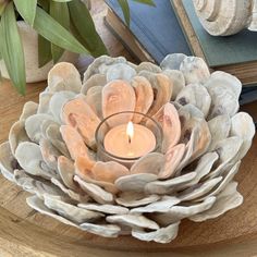 a candle is lit in front of some books on a table with an arrangement of seashells