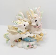 two white unicorn figurines sitting on top of each other