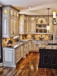 a large kitchen with wooden floors and white cabinetry, marble counter tops and an island