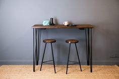 two stools sitting on top of a wooden table next to a vase and candle