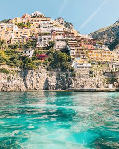 the water is crystal blue and clear with houses on it's hillside in the background