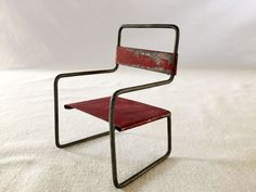 a red chair sitting on top of a white floor next to a metal frame structure