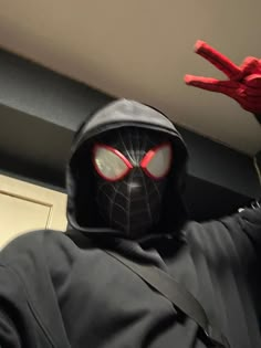 a person in a spider man costume is holding his arm up to the ceiling with one hand