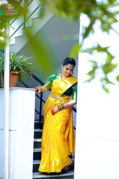 a woman in a yellow and green sari is standing on the steps with her arms outstretched