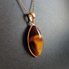 ITEM DESCRIPTION: >>The pendant is made from Solid 14K Yellow Gold. Gemstone used is absolutely natural and ethically sourced. >>Natural Tiger Eye in cabochon marquise shape with bezel setting is studded on it with utmost precision. >>This is a minimalist design and is absolutely hassle-free and everyday jewelry. Gem: Tiger Eye Gem size: 12x22 mm Marquise Gem weight: 11.55 carats Gold purity: 14K (58.33% approx.) Gold weight: 0.58 grams Gross weight: 2.89 grams The Gold purity is guaranteed and Fine Jewelry Gemstone Pendant For Gift, Teardrop Pendant Jewelry With Bezel Setting, Gift Jewelry Teardrop Pendant With Bezel Setting, Gift Jewelry With Bezel Setting In Teardrop Pendant Shape, Teardrop Bezel Set Necklace Gift, Teardrop Cabochon Necklace For Anniversary, Gift Teardrop Pendant Jewelry With Bezel Setting, Anniversary Cabochon Teardrop Necklace, Anniversary Teardrop Cabochon Necklace