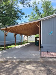 an empty parking lot in front of a building with a large wooden carport on the side