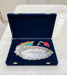 a silver tray with a feather, umbrella and other items in it on a table