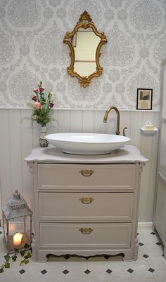 a white sink sitting under a mirror next to a wall mounted faucet in a bathroom