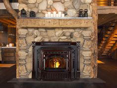 a fire place in a stone fireplace surrounded by logs and rocks with candles on the mantle