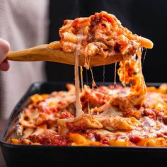 a person holding a wooden spoon full of cheesy pasta