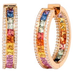 18 Karat Rose Gold 9.33 Carat Multi-Color Sapphire and Diamond Hoop Earrings The enchanting rainbow multi-sapphire and diamond full hoop are gratifying. The solitaire identical size princess cut multi-sapphires in channel setting enclosed within an equivalent layer of micro pave set diamonds on either side is distinctive in its very form. The delicateness of the identically cut and matching shape of the sapphires surround the hoop’s beauty. The elegant rose gold box setting leveled up by the dia Luxury Multi-stone Gold Hoop Earrings, Sapphire Earring, Modern Hoop Earrings, Sapphire And Diamond Earrings, Diamond Huggies, Channel Setting, Multi Sapphire, Hoop Design, Mini Hoop Earrings