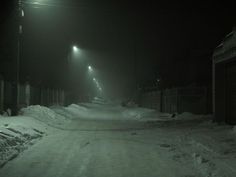 a dark street is covered in snow at night