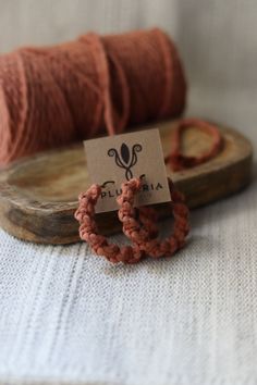 two bracelets sitting on top of a wooden board next to a spool of yarn