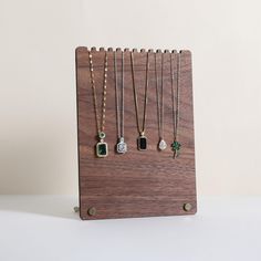 four necklaces are hanging on a wooden stand