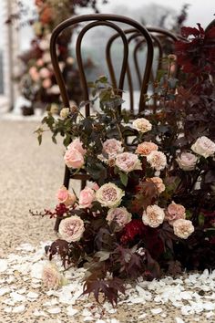 a bunch of flowers sitting on the ground next to a chair with petals all over it