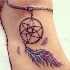 a woman's foot with a tattoo on it that has a dream catcher and feathers