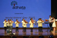 a group of children playing instruments on stage in front of a large screen with the words world elders'day