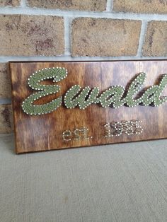 a wooden sign with the word souvenir written in beading on it next to a brick wall