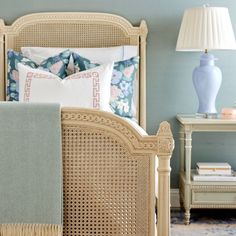 a bedroom with blue walls and white wicker bed frame, nightstands and lamps