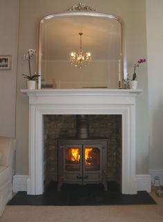 a fireplace with a mirror above it and a fire place in the middle that is lit