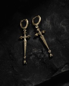 A blade of cryptic provenance drips ebony beads, having paid witness to magick’s wicked creeds. Sword earrings with hilts forming pointed gothic crosses - the symbol in our Ask & Embla logomark. At the point of each sword hangs a black crystal gem. Ear posts made from 925 Silver - kinder to sensitive skin. Sold as a pair. Each piece is lovingly crafted by hand, under ethical working conditions. Please allow for minor imperfections that are true to handcrafted jewelry. No two pieces are the same Afro Jewelry, Gothic Crosses, Dragon Earrings, Studs Earrings, Online Jewelry Store, Black Crystals, Crystal Gems, Ear Studs, Black Beads