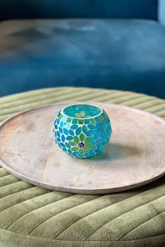 a blue and green vase sitting on top of a wooden tray next to a couch