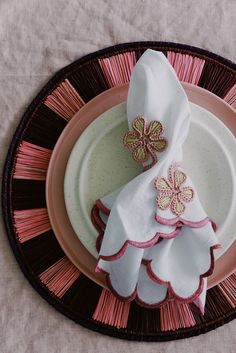 a pink and white plate topped with two napkins next to a flower shaped dish cloth